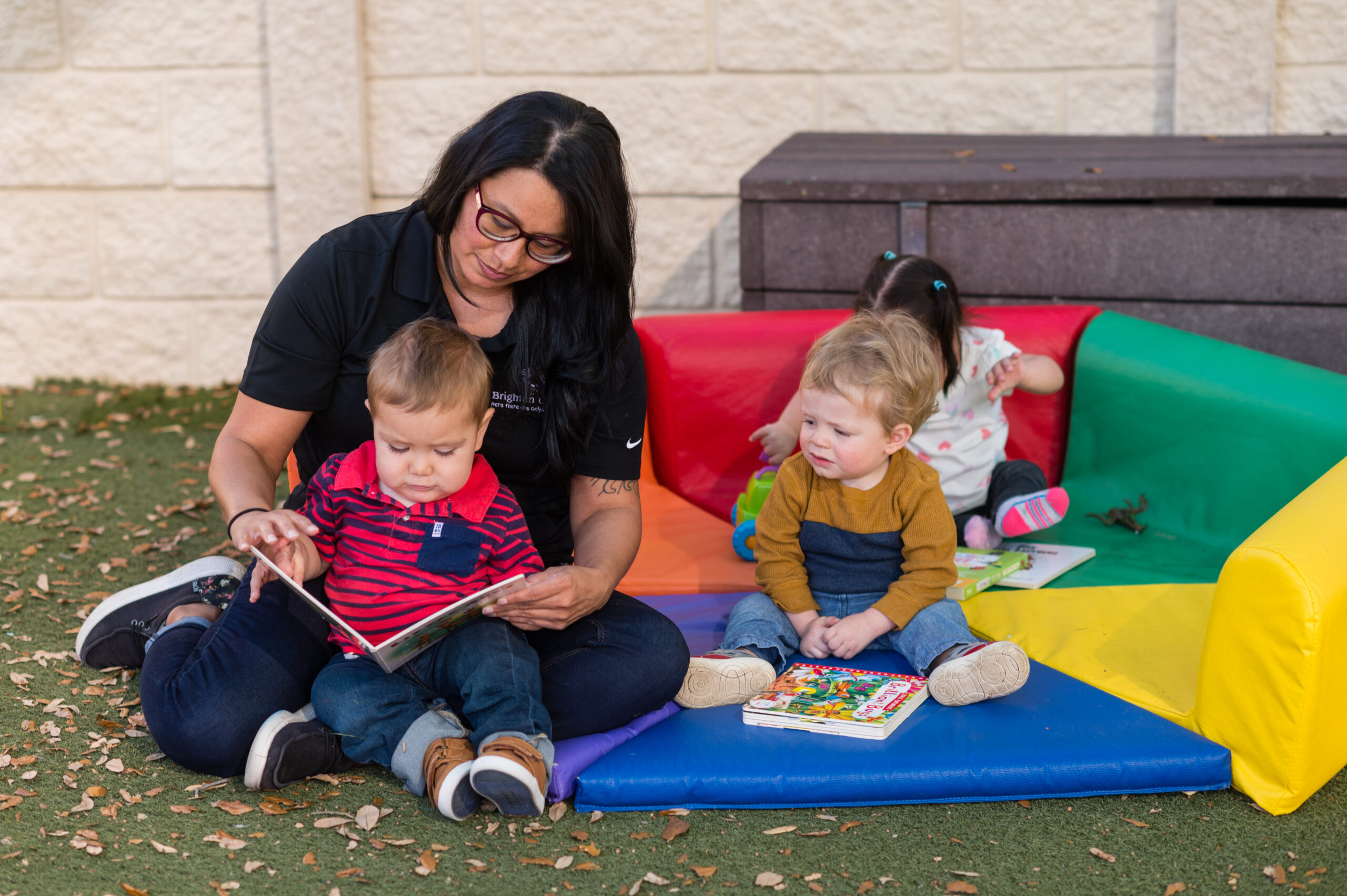 Brighton Preschool Teacher Reading to her Child Students Outsite